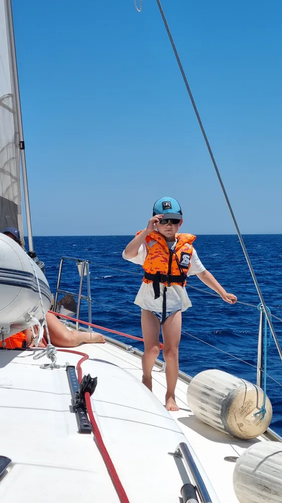 Kind mit Schwimmweste an Deck einer Segelyacht